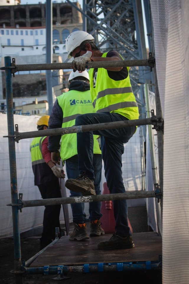 Semi-skilled construction workers in high-visibility safety vests and hard hats navigating scaffolding, illustrating Smart Agnes’s dependable site support and essential labor manpower solutions in Qatar.